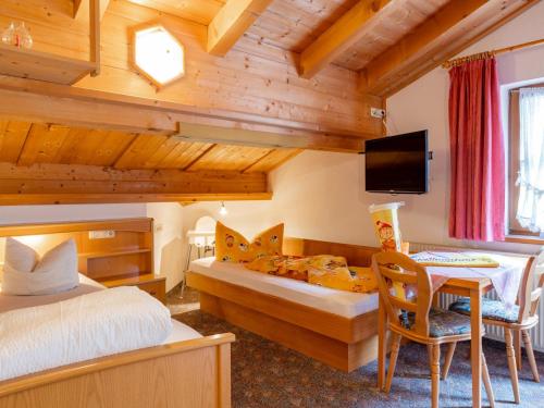 a bedroom with two beds and a table and a tv at Ferienhaus Dias in Kappl