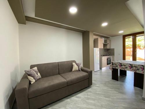 ein Wohnzimmer mit einem braunen Sofa und einer Küche in der Unterkunft Suite GuestHouse a pochi passi dal mare in Sassari