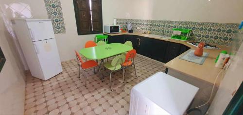 una cucina con tavolo e sedie verdi e frigorifero di La cascade a Houmt Souk