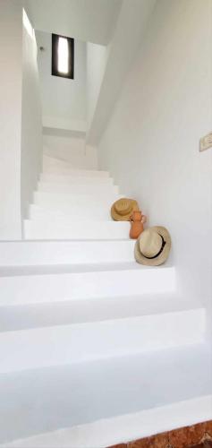 a white room with two hats sitting on the stairs at La cascade in Houmt Souk