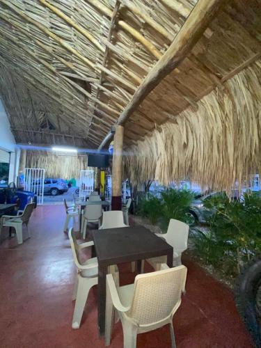 a patio with a table and chairs under a straw roof at HOTEL SAN NICOLÁS in Cereté
