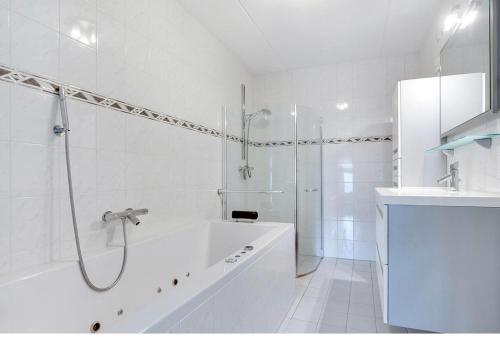 een witte badkamer met een bad en een douche bij Chico in Almere