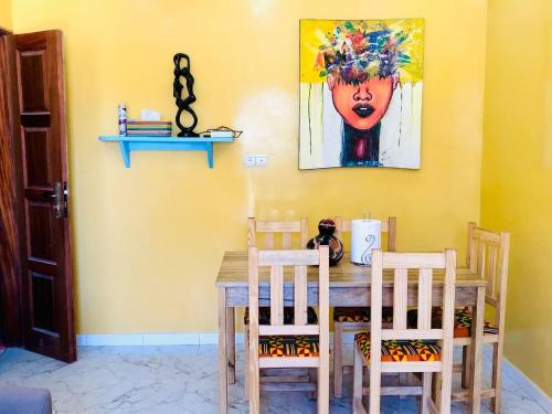ダカールにあるFadidi Houseのダイニングテーブル(椅子2脚付)が備わります。壁には絵画が飾られています。