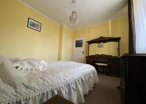 a bedroom with a white bed and a dresser at Апартамент Панорама Трявна - кът за отдих, въздухолечение и почивка in Tryavna