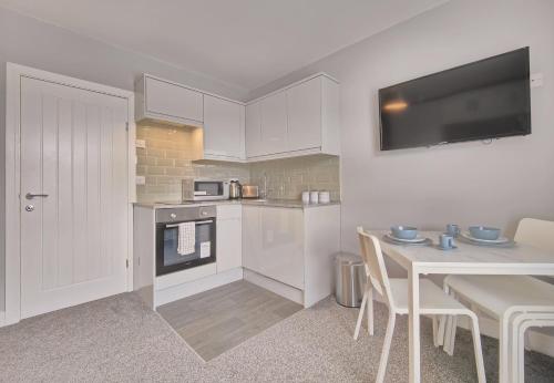 a kitchen with white cabinets and a table with chairs at Charming Holiday Home in Hazel Grove - Self Catering Apartment 2 in Hazel Grove