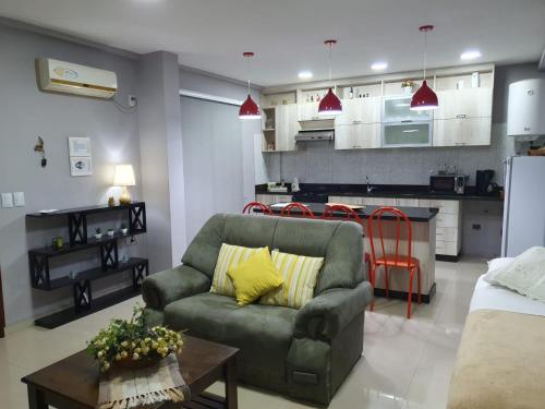 a living room with a couch and a kitchen at Martina Apart in Puerto Iguazú