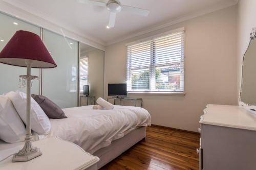 シドニーにあるFamily Stay with Idyllic Sun-drenched Courtyardのベッドルーム(白いベッド1台、赤いランプ付)