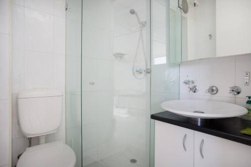 Un baño con inodoro, lavabo y ducha. en 'Bondi Fairview' Coastal Panorama with Balcony, en Sídney