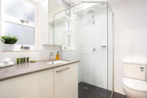a white bathroom with a shower and a sink at Live Like a Sydney Local in Trendy Marrickville in Sydney