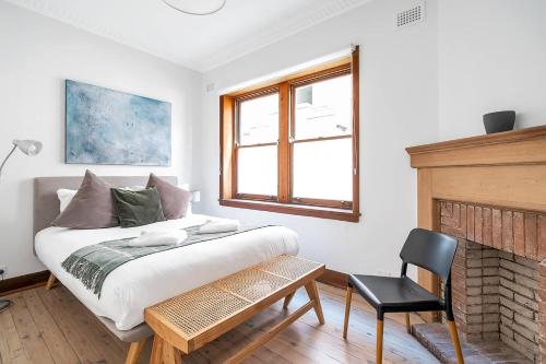 um quarto com uma cama, uma cadeira e uma lareira em A South Bondi Family Hideout for Beach Aficionados em Sydney