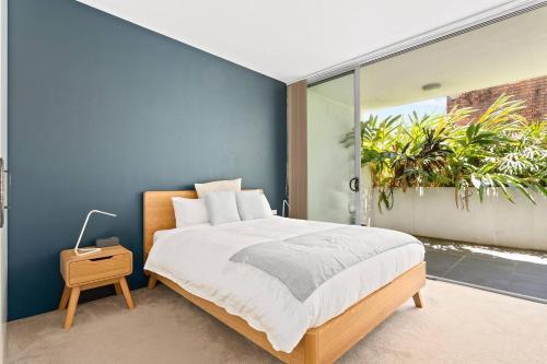 a bedroom with a large bed and a blue wall at Sunshine Pacific - A Spacious Boutique Stay in Sydney