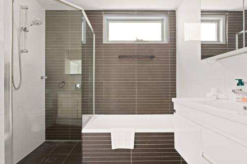 a bathroom with a shower and a tub and a sink at Sunshine Pacific - A Spacious Boutique Stay in Sydney