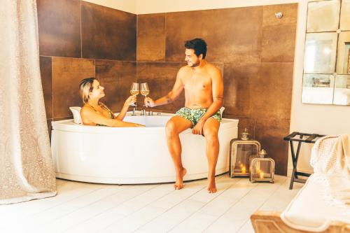 a man and woman sitting in a bath tub with champagne at Eksōtika in Oliveri