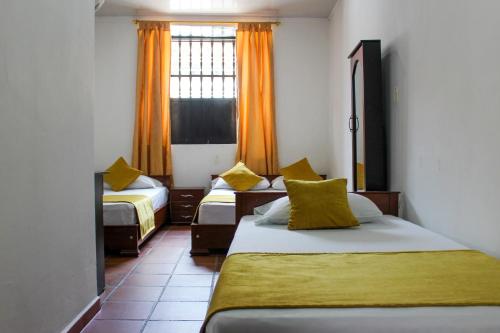 a hotel room with two beds and a window at Hotel Colonial San Felipe in Girón