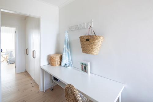 Port AdelaidePearl, Designer Beachfront Retreat, Semaphore Park的白色餐桌,墙上装有篮子