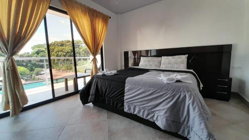 a bedroom with a large bed and a large window at Katara Boutique Hotel in Mariquita