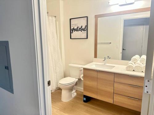 y baño con aseo, lavabo y espejo. en Modern Apartment Downtown Tacoma near the convention center, Free Netflix , King size bed & futon sofa bed , AC, Great Amenities Rooftop, self-check-in, en Tacoma