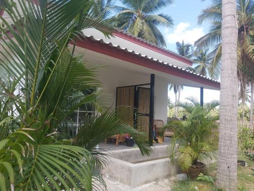 a house with a porch and some palm trees at Nice Home Stay at Samroiyod in Baanphakrimlay 