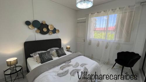 a white bedroom with a bed and a window at VILLA PHARE CARAÏBES Guadeloupe in Le Moule