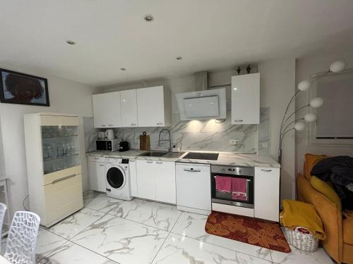 une cuisine avec des armoires blanches et un four à plaques de cuisson dans l'établissement Les chambre de amour, à Urrugne