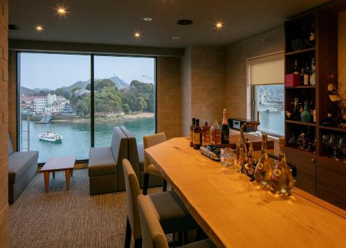 a room with a long wooden table with a view of a river at Sakura Hotel Onomichi Ekimae in Onomichi