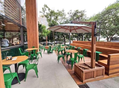 a patio with tables and chairs and an umbrella at Magníficos Ap Luxo - 43mts e 63mts, 1 ou 2 Qtos in São Paulo