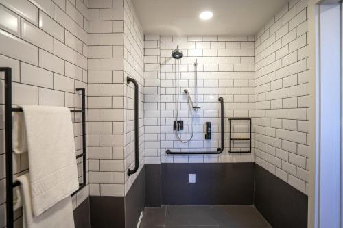 uma casa de banho em azulejos brancos com um chuveiro e um lavatório. em ibis Guarapuava em Guarapuava