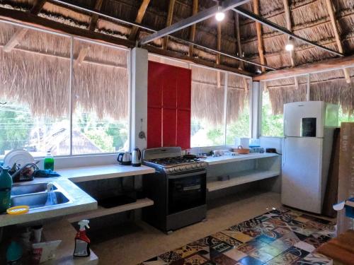 a kitchen with a stove and a refrigerator at Maui Hostels Tulum in Tulum