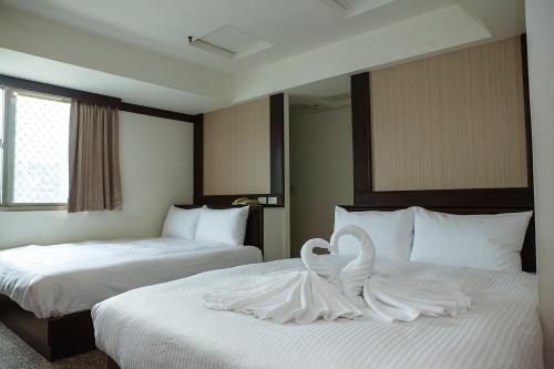 a hotel room with two beds with white sheets at YUAI FU HAO Hotel in Taichung
