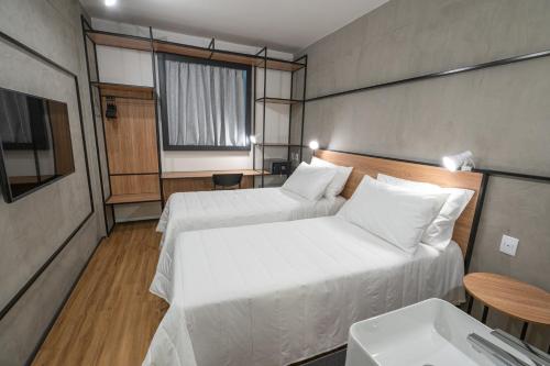 a small room with two beds and a sink at ibis Guarapuava in Guarapuava