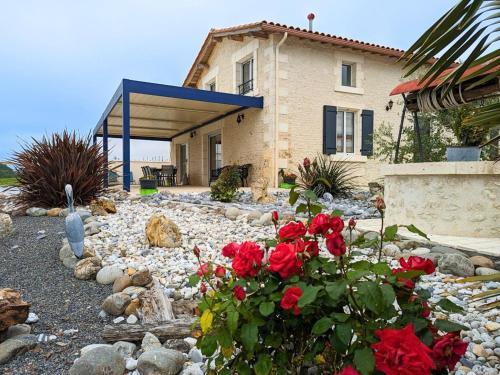 a house with red roses in the front yard at Gîte Charentais avec piscine, terrasse, et pêche - confort moderne et charme rural - FR-1-653-87 in Salles-de-Barbezieux