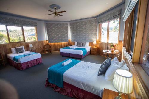 Habitación de hotel con 2 camas y ventilador de techo. en Robyn's Nest Lakeside Resort en Merimbula