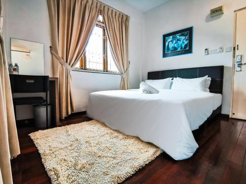una camera da letto con un grande letto bianco e una finestra di Semi detached At Tabuan Jaya,13BR By Natol Homestay-London a Kuching