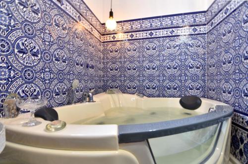 Baño con azulejos azules y blancos en la pared en La Casa de Reyes en Peñaflor
