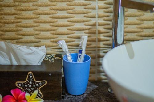 two toothbrushes in a blue cup next to a table at Pondok Raamshanti Lembongan in Nusa Lembongan