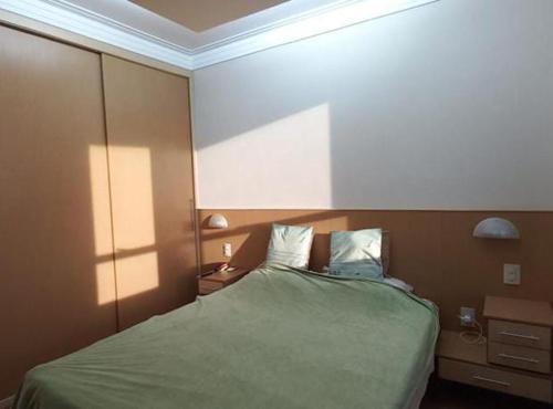 een slaapkamer met een groen bed met 2 kussens bij Londrina Flat Hotel - Apto completo in Londrina