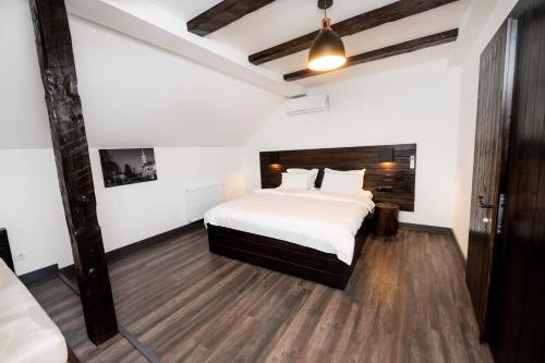 a bedroom with a large white bed and wooden floors at Casa Bolta Rece in Sighetu Marmaţiei