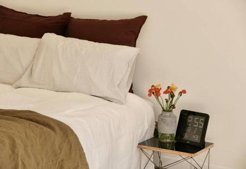 a bed with a clock and flowers on a night stand at Collingwood Studio Hideaway in Melbourne