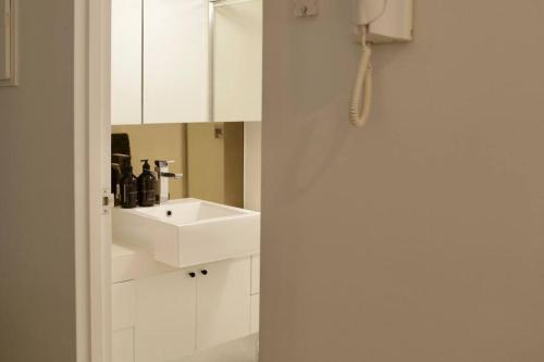 a white bathroom with a sink and a mirror at Collingwood Studio Hideaway in Melbourne