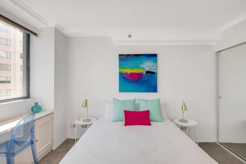 a white bedroom with a large bed with a red pillow at Top of the Town with Sydney CBD at its Doorstep in Sydney