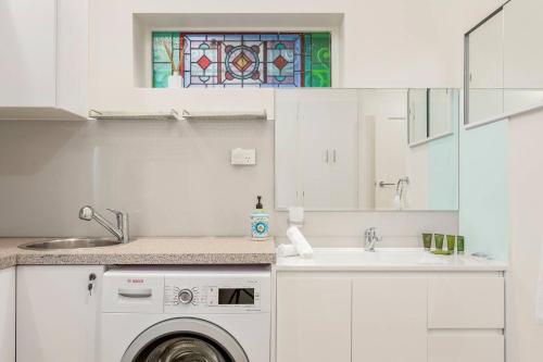 uma cozinha com uma máquina de lavar roupa e um lavatório em 'Lady Beatle' Quirky Character Terrace near Harbour em Sydney