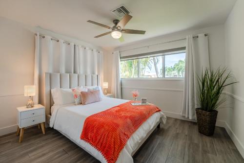 a bedroom with a bed with a ceiling fan and a window at Life is Blue in Fort Lauderdale