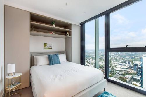 una camera con un letto bianco e una grande finestra di The View on Elizabeth - Chic City Centre Living a Melbourne