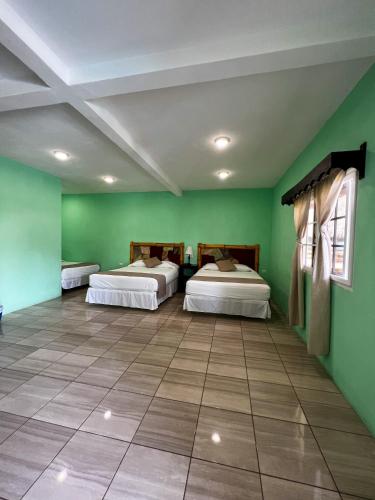two beds in a room with green walls at Hotel Pazifico en Monterrico in Monterrico