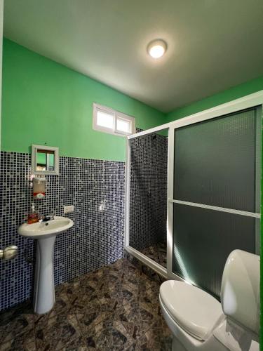 a bathroom with a shower and a toilet and a sink at Hotel Pazifico en Monterrico in Monterrico