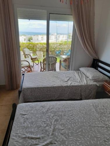 2 bedden in een slaapkamer met uitzicht op een patio bij Appartement Al cudia smir in Fnidek