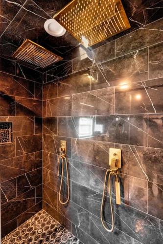 a large bathroom with a shower with brown tiles at The Sinatra - Fun 5BD Home Huge Pool Game Room in Round Rock