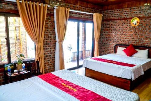 a bedroom with two beds and a brick wall at D&D riverside Homestay in Xuân Sơn