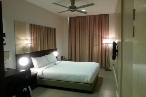 Habitación de hotel con cama y ventilador de techo. en 101 Hotel Bintulu, en Bintulu