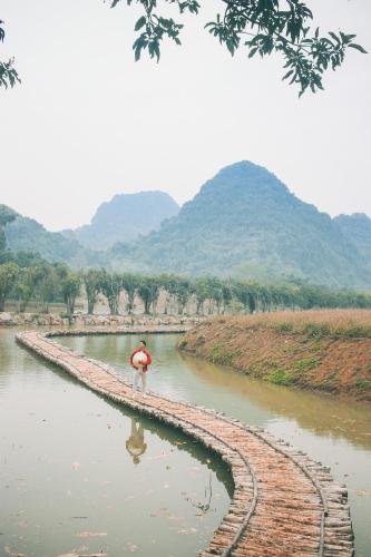 a man walking along a river with mountains in the background at Thung Nham Resort in Ninh Binh